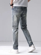 Back side of men’s washed slim fit jeans in light-wash denim with subtle fading and stitched classic back pockets