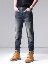 Men’s dark-wash slim fit denim jeans with rolled cuffs paired with tan suede work boots in washed straight leg style