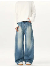 Men’s washed wide leg denim jeans in faded blue wash with subtle distressing and raw hem detailing
