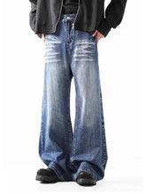 Men’s wide leg jeans in faded blue denim with subtle whiskering and frayed hems for a casual look