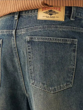 Men’s washed wide leg blue denim jeans with a beige designer label off-shore yachting club on the back waistband