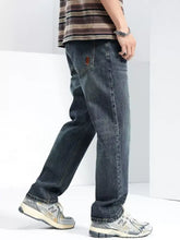 Back side of men’s washed wide leg jeans in dark-wash denim with subtle faded texture and small brown patch on pocket