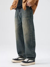Men’s washed wide leg jeans in faded dark wash denim with subtle distressing styled with an orange striped shirt