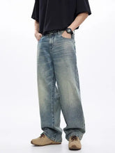 Men’s washed wide leg jeans in faded light blue denim with subtle distressing and raw hem detailing