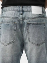 Men’s washed wide leg light-wash denim jeans with a faded distressed look shown from the back with classic pockets