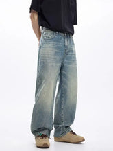 Men’s washed wide leg jeans in light-wash denim with a relaxed fit and faded distressing along the thighs