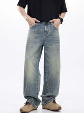 Men’s washed wide leg jeans in faded light blue denim with subtle distressing and raw hem detailing