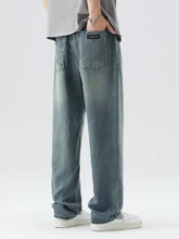 Back side of men’s washed wide leg relaxed fit blue denim jeans with black fashion label on the rear pocket