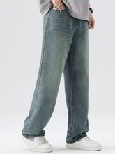 Men’s washed wide leg relaxed fit jeans in faded blue green denim with subtle distressing and a relaxed fit