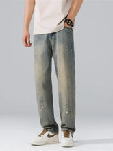 Men’s wide leg jeans in washed denim with a faded distressed look and subtle paint splatter details