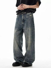 Men’s wide leg jeans in faded blue denim with distressed patches, classic stitching, subtle fading, and raw hem