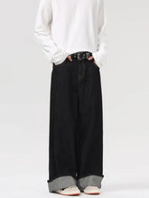 Black wide leg jeans with rolled cuffs revealing contrasting gray inner lining in denim material