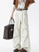 Men’s cream-colored wide leg cargo pants with multiple flap pockets and a brown belt in wide leg style