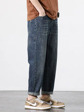 Dark-wash men’s wide leg jeans with relaxed tapered fit and rolled cuffs in durable denim material