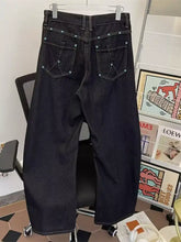 Back side of men’s wide leg jeans in dark-wash denim with silver studs on wide leg back pockets