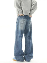 Men wide leg jeans in faded blue denim with subtle distressing and classic back pockets shown from the back side