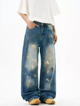 Men’s wide leg jeans in faded blue denim with distressed paint splatter detailing and a relaxed fit