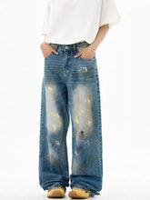 Men’s wide leg denim jeans in faded blue wash with distressed paint splatter patterns for casual wear