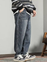Men’s wide leg jeans in faded blue denim with subtle whiskering and detailed stitching for a stylish casual look