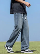 Men’s wide leg jeans in light-wash denim with a relaxed straight-leg cut and white drawstrings at the waist