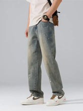 Men’s wide leg washed denim jeans with a faded distressed look and subtle paint splatter details