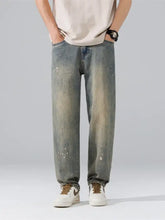 Men’s wide leg washed denim jeans with faded distressed look and subtle paint splatter detailing