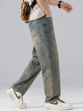 Men’s wide leg washed denim jeans with a faded distressed look and white paint splatter details