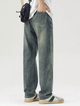 Men’s wide leg jeans in washed denim with a faded distressed look and classic back pocket stitching shown from the back