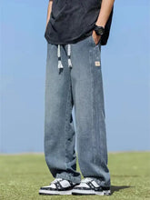 Men’s wide leg jeans in light-wash denim with white drawstrings and a small beige patch on the side seam
