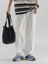 Black denim tote bag with a single front pocket and sturdy handles paired with men’s wide leg jeans machine wash tumble dry