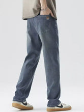 Back view of men’s wide leg blue denim jeans with relaxed fit subtle fading and brown patch on the pocket
