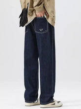 Back side of men’s wide leg jeans in dark blue denim with subtle white stitching detail on the back pocket
