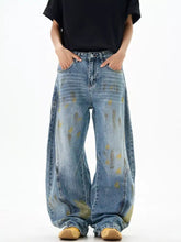 Men’s wide leg denim jeans with faded blue wash and yellow paint splatter accents