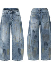 Men’s wide leg paint splatter jeans in light-wash denim with distressed details in muted yellow and gray tones