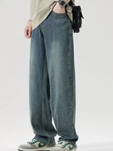 Men’s wide leg relaxed fit jeans in faded blue denim with subtle distressing and raw hem detailing
