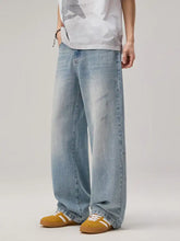 Men’s wide leg wash jeans in light-wash denim with a relaxed fit and subtle distressed details