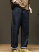 Men’s wide leg washed jeans in dark indigo denim with relaxed straight-leg cut and rolled cuffs showing lighter lining