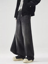 Men’s black wide leg washed jeans with faded distressed finish and visible stitching details in denim material