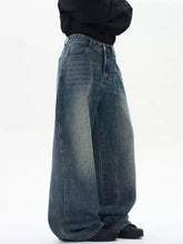 Men’s wide leg washed jeans in faded medium-blue denim with visible stitching and a relaxed oversized fit