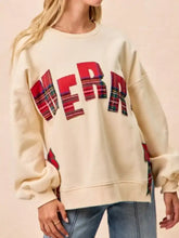 Cream-colored oversized christmas sweatshirt with bold red plaid merry lettering and matching sleeve patches made of stretchy material