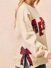 Cream-colored merry bow slit crew neck christmas sweatshirt with bold red green plaid lettering and matching bow in slightly stretchy material machine wash cold
