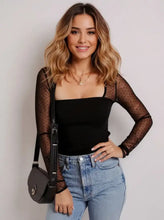 Black crossbody bag with sleek minimalist design and subtle metallic hardware paired with mesh sleeve square neck bodysuit