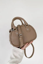 Taupe leather handbag with gold hardware and shoulder strap