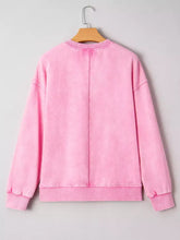 Pink oversized mineral wash sweatshirt with ribbed cuffs and hem hanging on wooden hanger machine wash care instructions