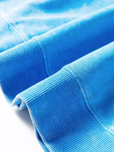 Blue ribbed knit cuffs on a mineral wash double patched pocket sweatshirt with machine wash care instructions