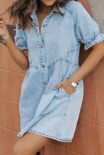 Light blue mineral wash denim dress with short puffed sleeves and button-front design featuring a ruffle detail