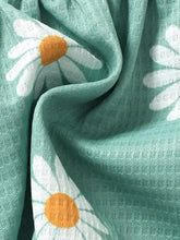 Teal floral waffle blanket with white daisies beside mint green peplum blouse pants set