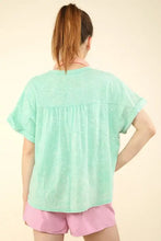 Woman in mint green washed knit top with notched short sleeve and pink shorts