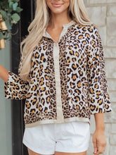 A women’s mixed leopard patchwork button-up blouse with three-quarter sleeves and cream inner lining