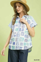 Women’s short-sleeved blouse shirt features mixed media print with blue geometric shapes on a light background